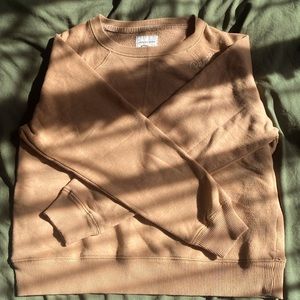 yellowish sweatshirt with “peace” embroidered on the shoulder